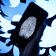 In this photo illustration, a thumbprint is displayed on a mobile phone as the logo for the Twitter social media network is projected onto a screen on August 09, 2017 in London, England.